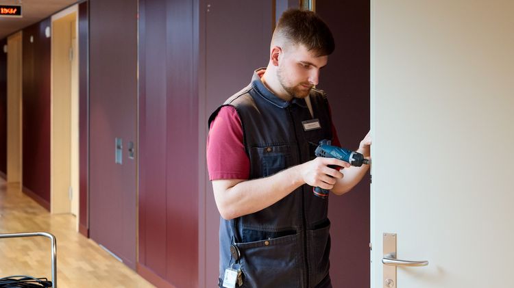Mann repariert Zimmertüre. 