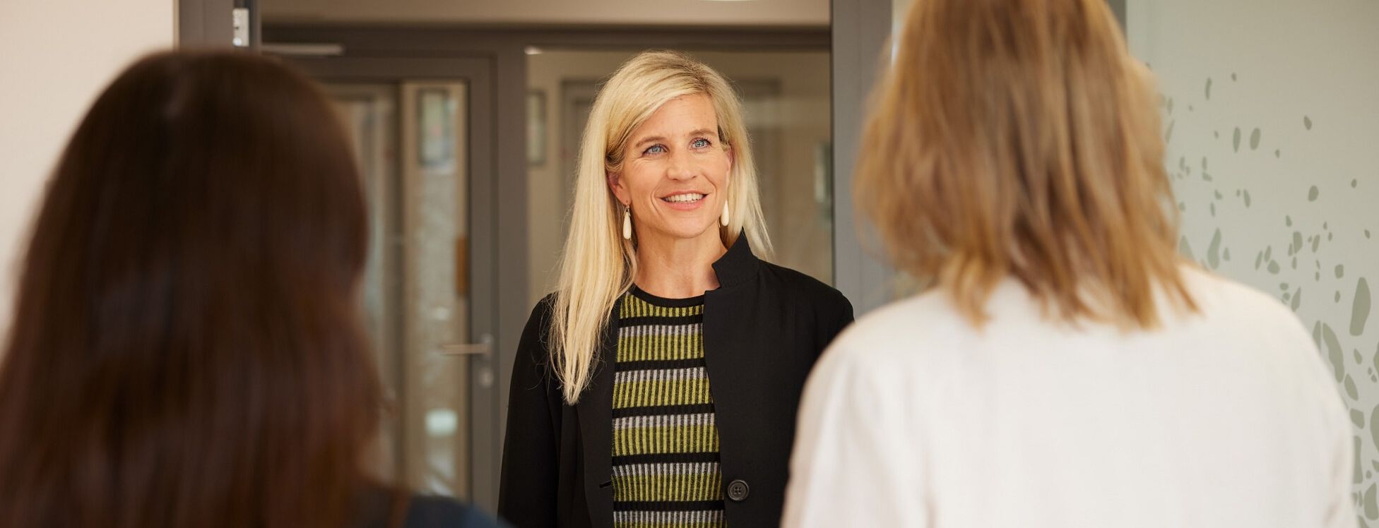 Frau begrüsst Patientin am Eingang. 